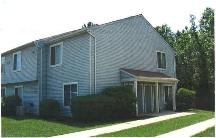 A two-story Lexington Village building with blue-gray siding, a covered entry, and a green lawn