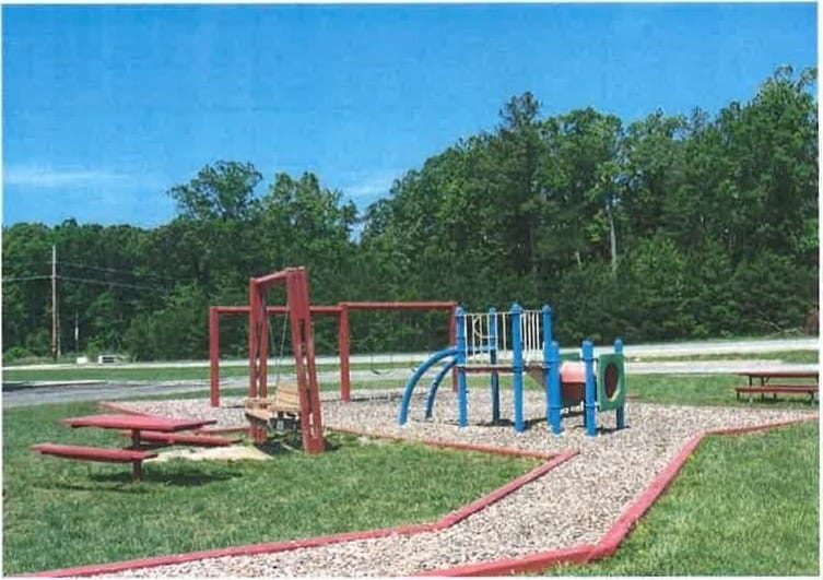 The community playground at Lexington Village, with a slide, swings, and a picnic table on the lawn